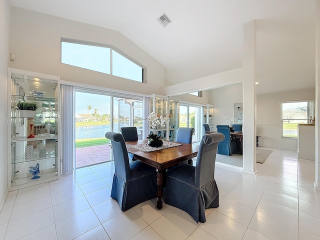 tiled dining space featuring decorative columns and high vaulted ceiling