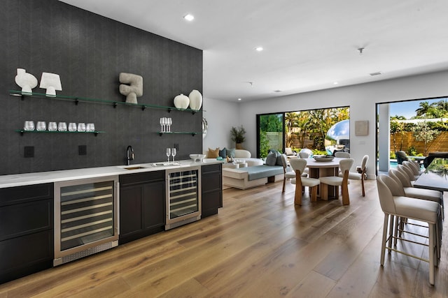 bar featuring light hardwood / wood-style floors, sink, and beverage cooler