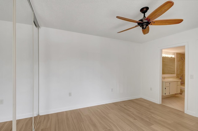 unfurnished bedroom with a closet, ensuite bath, ceiling fan, and light hardwood / wood-style floors