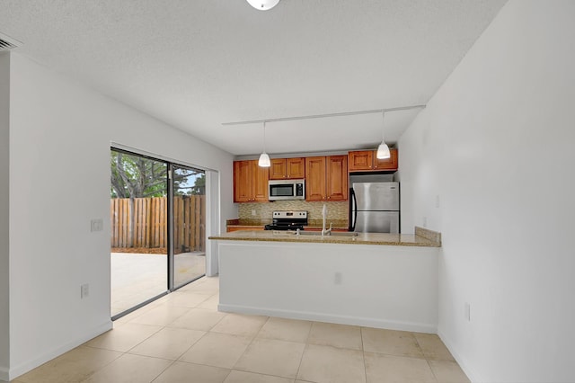 kitchen featuring pendant lighting, backsplash, track lighting, sink, and stainless steel appliances