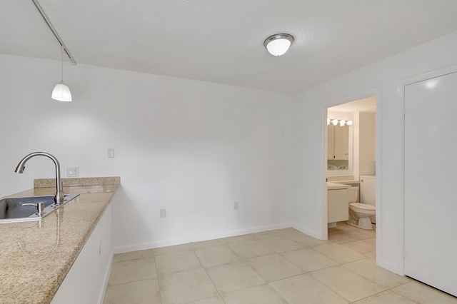 interior space featuring pendant lighting, light stone counters, and sink