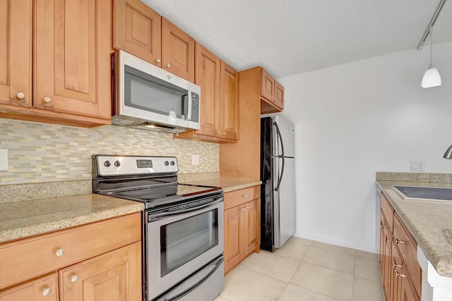 kitchen featuring decorative backsplash, appliances with stainless steel finishes, sink, light tile patterned floors, and decorative light fixtures