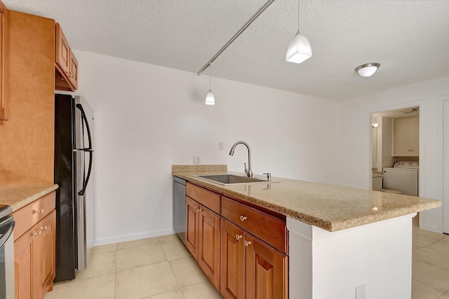 kitchen with sink, appliances with stainless steel finishes, decorative light fixtures, kitchen peninsula, and washer / clothes dryer