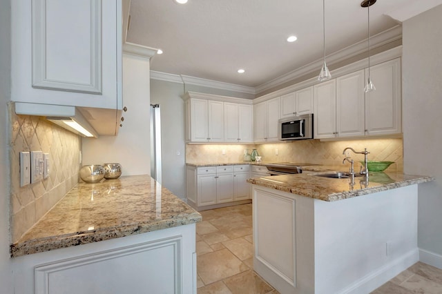 kitchen with white cabinetry, sink, stainless steel appliances, light stone counters, and kitchen peninsula