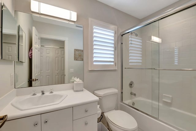 full bathroom featuring vanity, toilet, and bath / shower combo with glass door