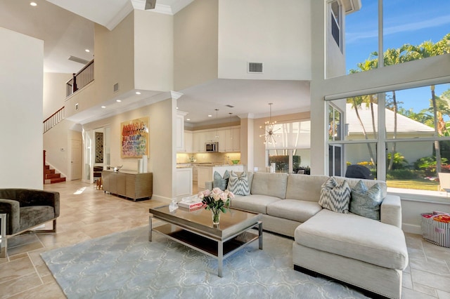 living room featuring a chandelier, a towering ceiling, a wealth of natural light, and crown molding