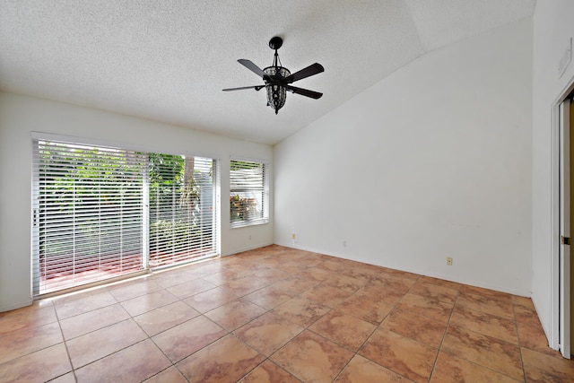 empty room with ceiling fan, vaulted ceiling, plenty of natural light, and light tile patterned flooring