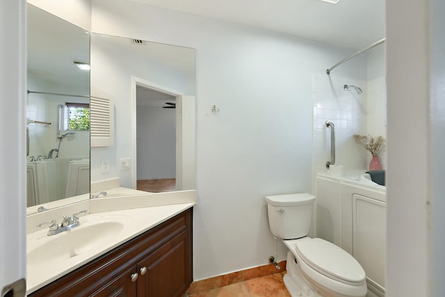 bathroom with toilet, vanity, tiled shower, and tile patterned floors