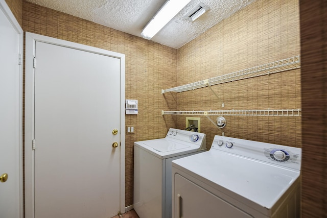 clothes washing area featuring independent washer and dryer and a textured ceiling