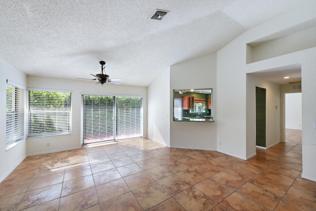 unfurnished living room featuring ceiling fan, light tile patterned floors, a textured ceiling, and vaulted ceiling