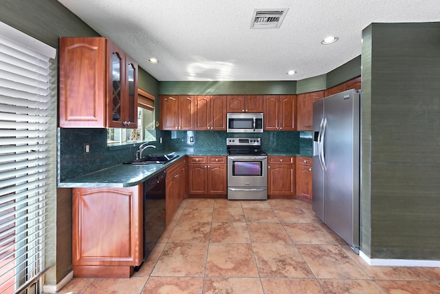 kitchen featuring dark stone countertops, sink, a textured ceiling, and appliances with stainless steel finishes