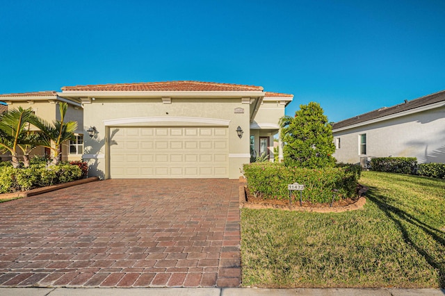 mediterranean / spanish-style house featuring a garage and a front lawn