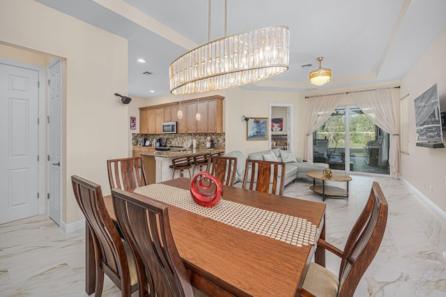 dining area with a raised ceiling and a notable chandelier