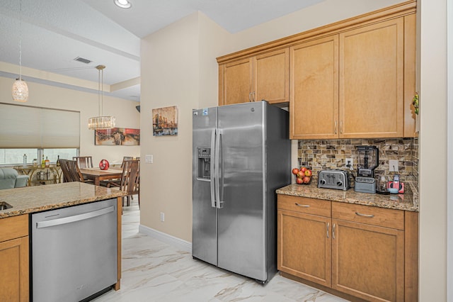 kitchen featuring lofted ceiling, pendant lighting, decorative backsplash, light stone countertops, and stainless steel appliances