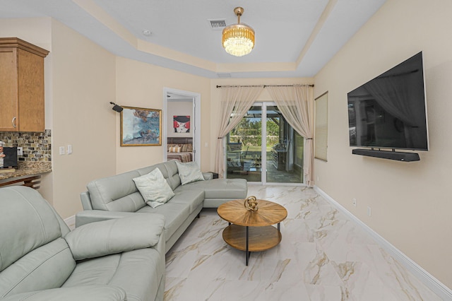 living room with an inviting chandelier and a tray ceiling