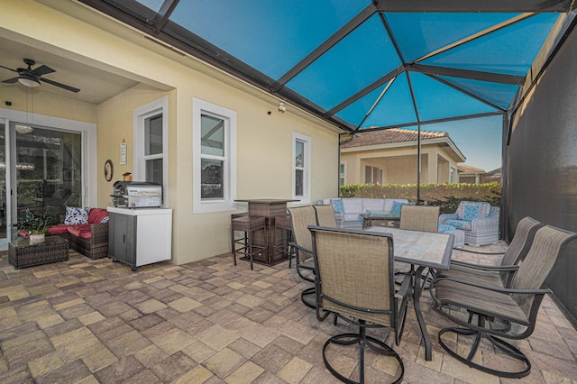 view of patio / terrace with ceiling fan, a bar, outdoor lounge area, and glass enclosure