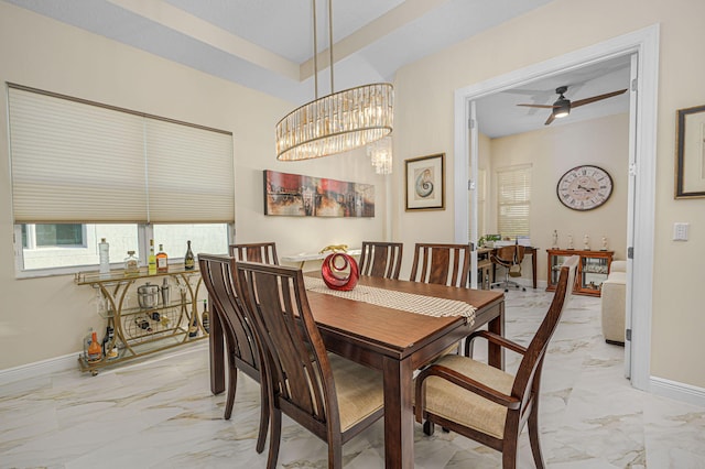 dining space featuring ceiling fan with notable chandelier and a tray ceiling