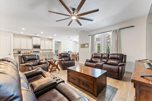 living room with a textured ceiling, ceiling fan, and sink