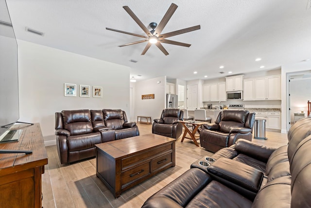 living room featuring a textured ceiling and ceiling fan