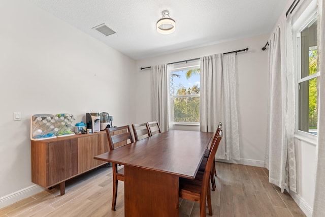 dining area with a textured ceiling and light wood-type flooring