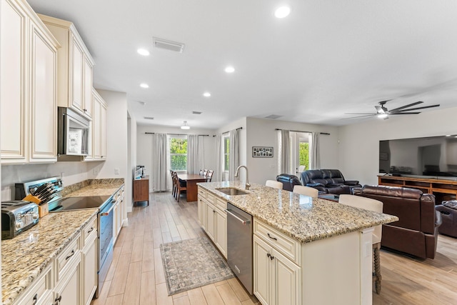 kitchen featuring cream cabinets, light stone counters, sink, and appliances with stainless steel finishes