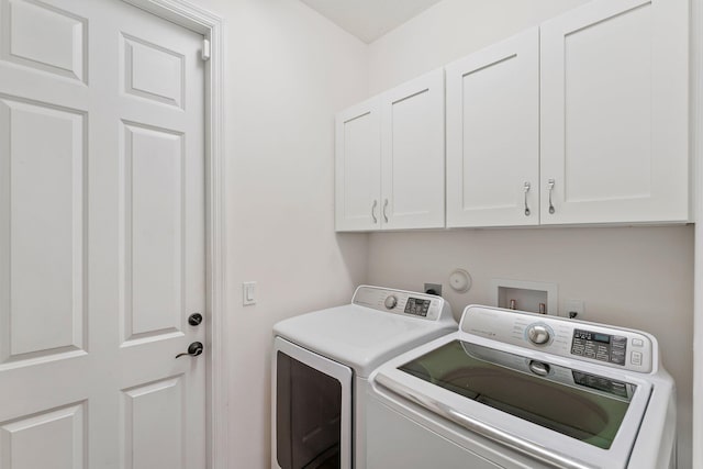 clothes washing area with cabinets and separate washer and dryer