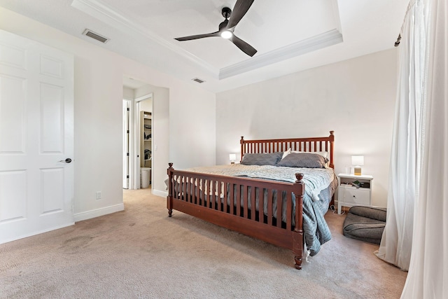 carpeted bedroom with ceiling fan and a tray ceiling