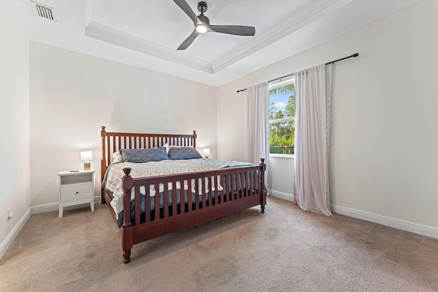 carpeted bedroom with a raised ceiling and ceiling fan