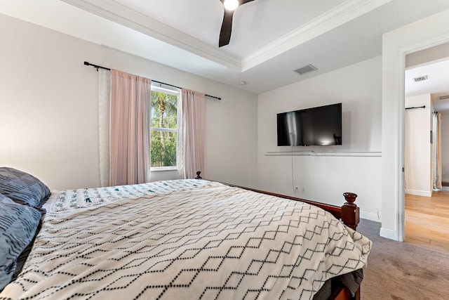 bedroom with carpet flooring, a raised ceiling, ceiling fan, and ornamental molding