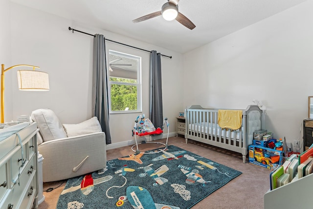 bedroom featuring a crib, light colored carpet, and ceiling fan