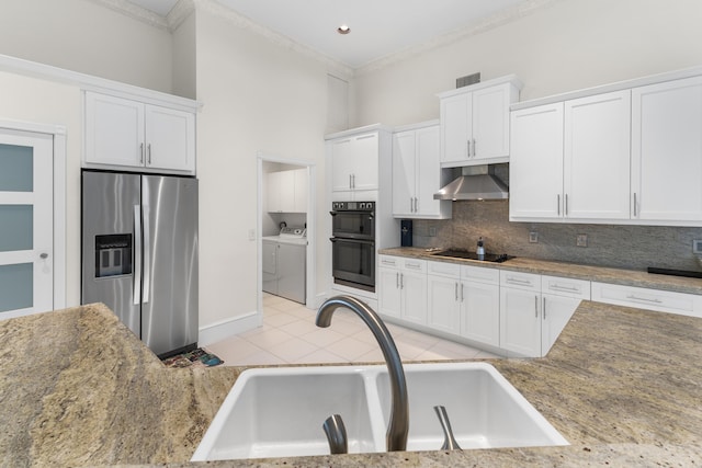 kitchen with independent washer and dryer, black appliances, ventilation hood, sink, and white cabinetry