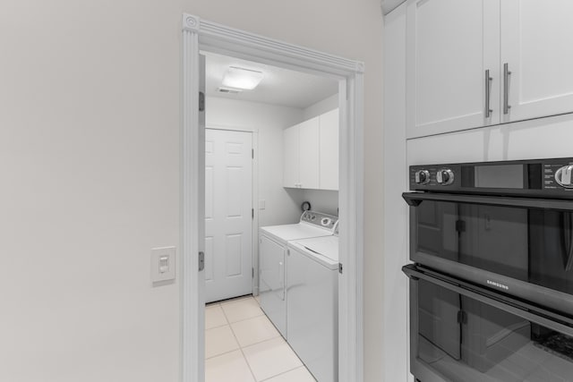 laundry room featuring light tile patterned flooring, separate washer and dryer, and cabinets