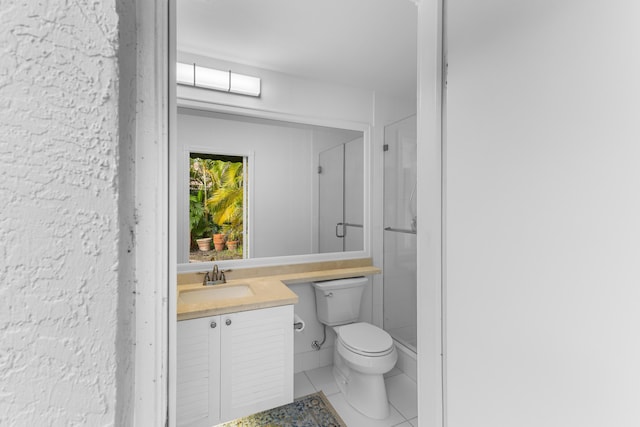 bathroom featuring toilet, tile patterned flooring, vanity, and a shower with shower door