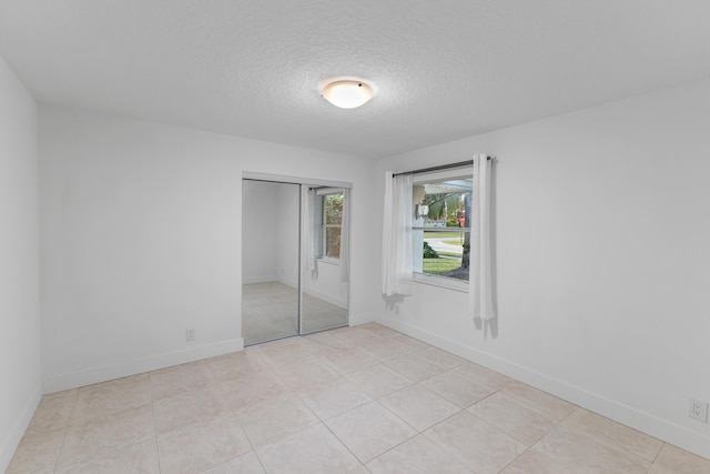 unfurnished bedroom with a textured ceiling, light tile patterned flooring, and a closet