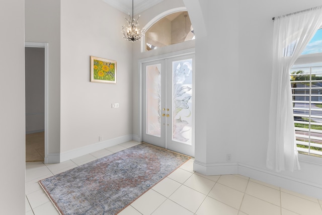 tiled foyer entrance with french doors, an inviting chandelier, and crown molding