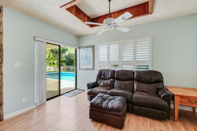 living room with ceiling fan, light wood-type flooring, and a textured ceiling