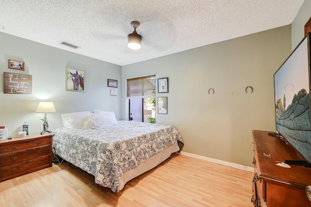 bedroom with a textured ceiling, light wood-type flooring, and ceiling fan