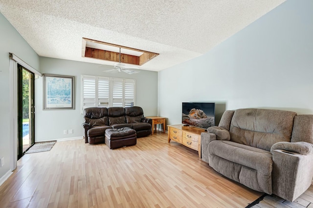 living room with a skylight, a textured ceiling, light hardwood / wood-style floors, and ceiling fan