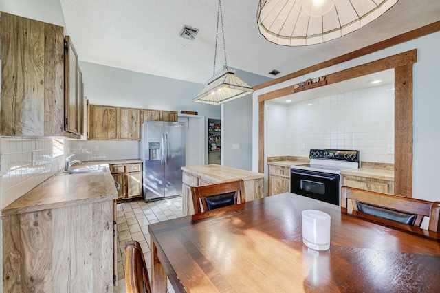 kitchen featuring decorative backsplash, stainless steel fridge, white electric range oven, sink, and hanging light fixtures