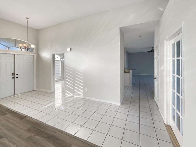 tiled foyer entrance featuring ceiling fan with notable chandelier