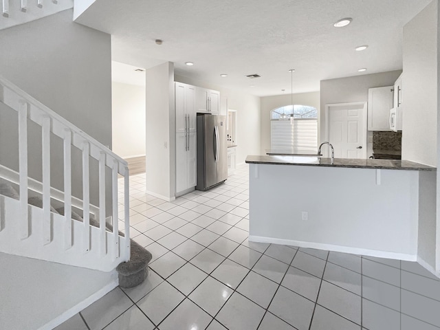 kitchen with kitchen peninsula, stainless steel fridge, decorative backsplash, pendant lighting, and white cabinetry