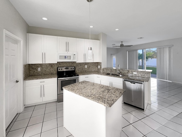 kitchen featuring sink, hanging light fixtures, kitchen peninsula, a kitchen island, and appliances with stainless steel finishes