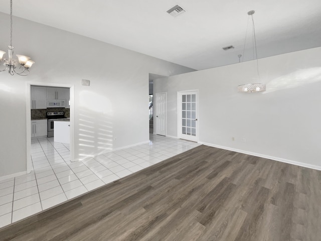 spare room featuring a notable chandelier and light hardwood / wood-style floors