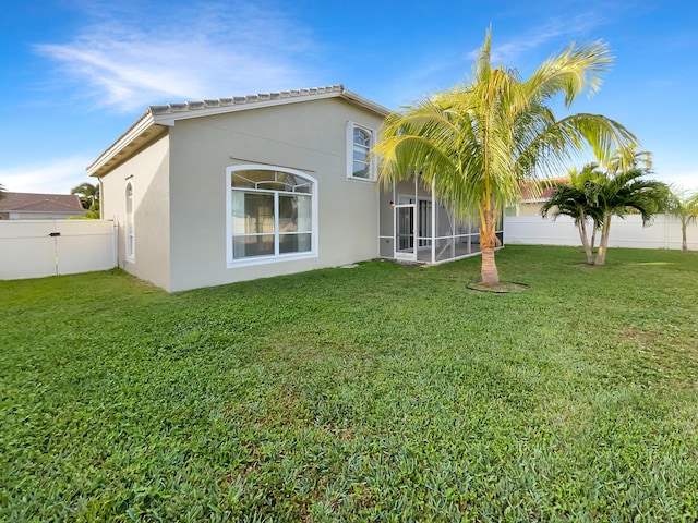 back of property featuring a lawn and a sunroom