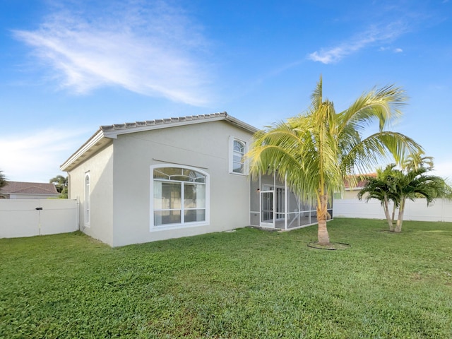 rear view of property featuring a sunroom and a lawn