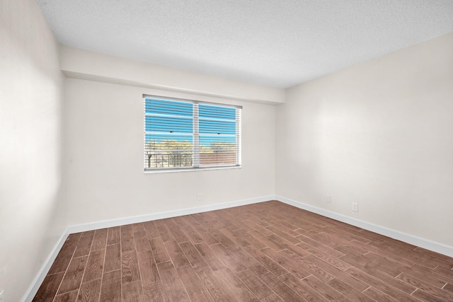 unfurnished room with dark hardwood / wood-style flooring and a textured ceiling