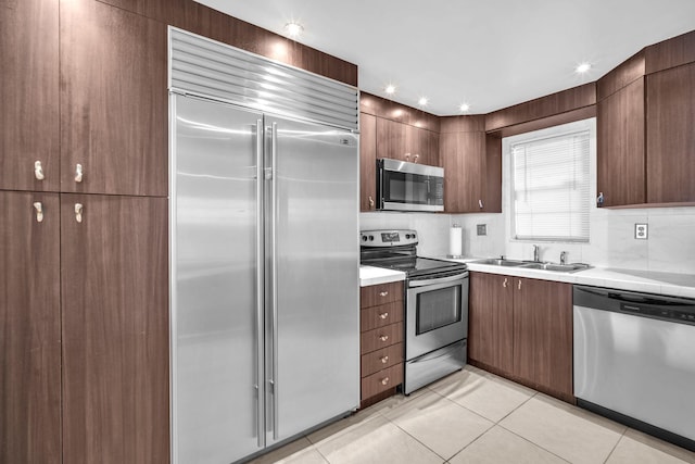 kitchen featuring light tile patterned flooring, appliances with stainless steel finishes, sink, and backsplash