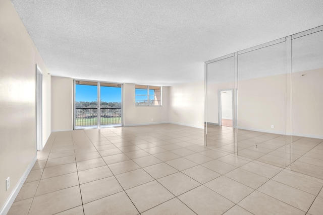 tiled spare room with expansive windows and a textured ceiling