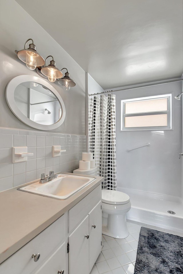 bathroom featuring vanity, tile patterned flooring, toilet, tile walls, and curtained shower