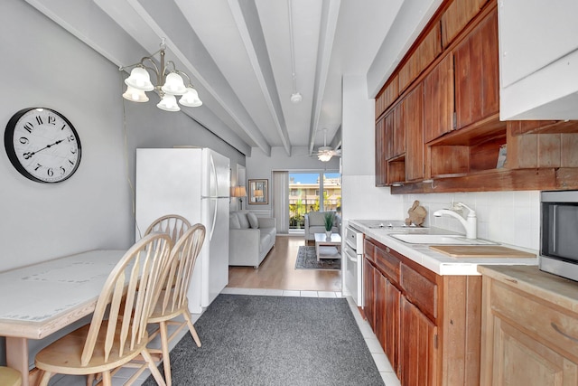 kitchen with decorative backsplash, sink, light tile patterned floors, beam ceiling, and white fridge